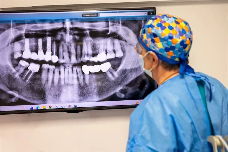 Doctor de las Clínicas Dentales Francisco Hernández Vallejo revisando una radiografía panorámica con implantes