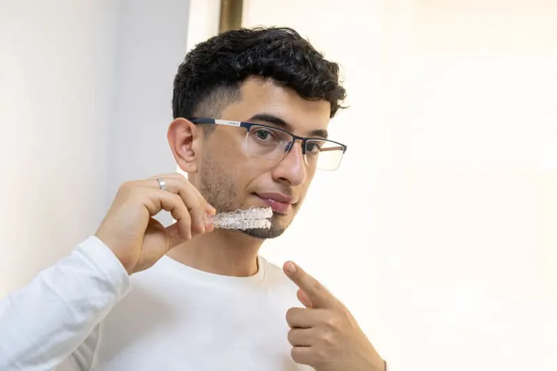 Paciente de las Clínicas Dentales Francisco Hernández Vallejo sosteniendo un alineador transparente Invisalign